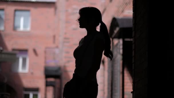 Silhouette eines schlanken jungen Mädchens auf dem Hintergrund der Stadt — Stockvideo