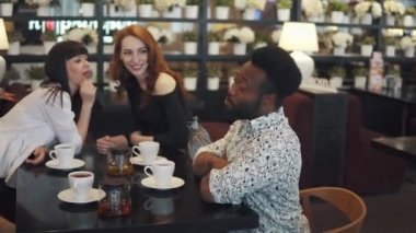 çok etnik gruptan oluşan şirket bir kafe ya da restoran gör. arkadaşlar ve konuşma birlikte eğlenin. iki kız ve bir sıcak kahve evde bir masada iki adam. Kızlar dedikodu içinde belgili tanımlık geçmiş