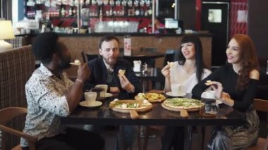 arkadaşlar birlikte pizza yemek. çok etnik gruptan oluşan şirket bir kafe ya da restoran gör. arkadaşlar ve konuşma birlikte eğlenin. iki kız ve bir sıcak kahve evde bir masada iki adam