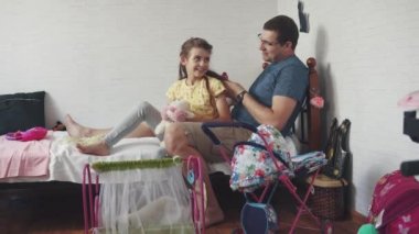 Genç Peder kızı çocuk odasında yatağın üstüne oturan bir oyuncak tarak ile tarak. Baba ve kızı birlikte vakit