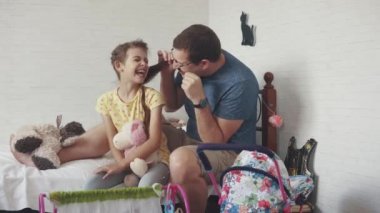 Genç baba küçük kızı ile vakit geçiriyor. Baba kızına pigtails bezleri, onunla çalış ve aptallar. Baba ve kızı arasında dostluk.