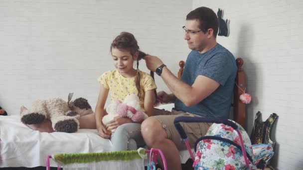 Le jeune père passe du temps avec sa petite fille. Papa tresse des nattes, joue avec elle et les imbéciles autour — Video