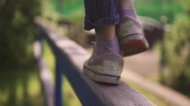 Enfants jambes gros plan. l'enfant est sur la barre transversale et équilibre dans l'air. le concept d'une enfance heureuse et sereine. au ralenti — Video