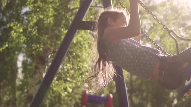 Gelukkig kind swingen op een schommel en lachen. vreugde en het geluk van de zomerdagen. Slow motion — Stockvideo