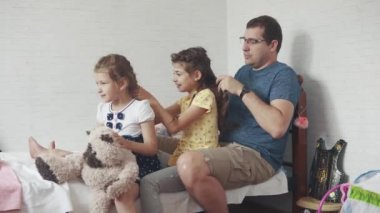 Baba ve iki küçük kızım evde. Baba, çocuklarla vakit geçiriyor. Babası at kuyruklu kızı için yapar.