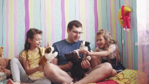 Ένας νεαρός πατέρας παίζει με τις κόρες του σε κούκλες στο παιδικό δωμάτιο — Αρχείο Βίντεο