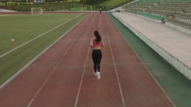 Hava. bir genç kız. arkadan görüntüleyin. Etrafta dolanan bir stadyumda sportif kadın