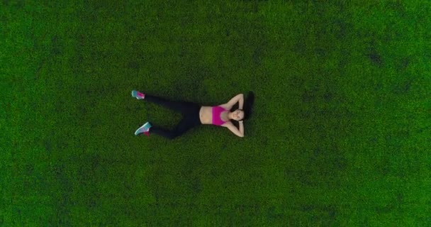 Sportovní žena odpočívá po cvičení ležící na trávě. pohled shora. rám z výšky — Stock video