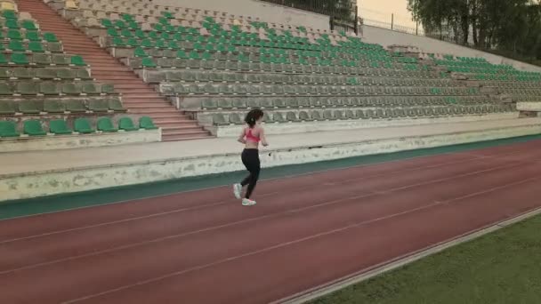 Aerial. jogging. sports girl running through the stadium. young woman jogging outdoors — Stock Video