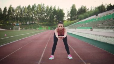 Eğitim önce ısınma. Genç kız spor giyim stadyumda germe yapıyor. ağır çekim