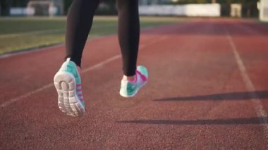Bayan spor ayakkabı yakın çekim bacaklar. kız parça stadyumda çalışır. Arkadan görünüm. ağır çekim
