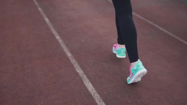 Fille coureuse jogging dans le stade. jeune femme sportive est engagée dans le sport en plein air. vue arrière. au ralenti — Video