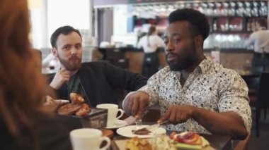 iki genç adam bir biftek bir restoranda yemek. iki arkadaş bir rahat restoranda bir masada oturmak ve eğlenceli konuşuyor.