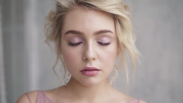 Detailní portrét krásná dívka s modrýma očima. Blondýnka s krásnou make-up a účes otevírá její oči a úsměv na kameru — Stock video