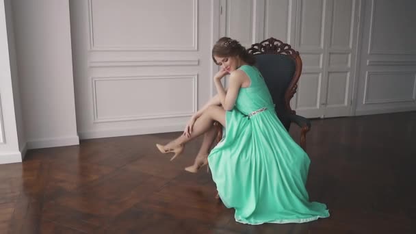 Fille en robe de cocktail assis sur une chaise et pend ses jambes — Video