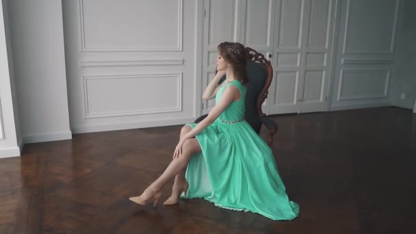 Fille en robe de cocktail assis sur une chaise et mignon sourire à la caméra — Video