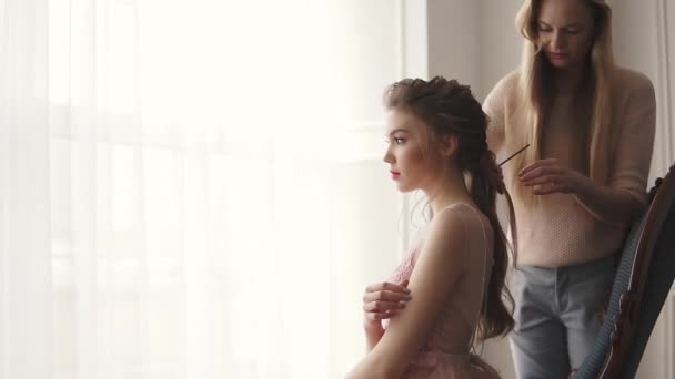 Kadeřnice má účes modelu. dívka v šatech koktejl se připravuje na oslavu — Stock video