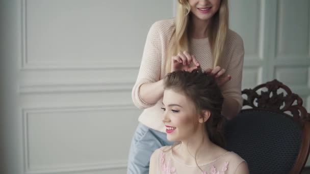 发型师做模特的发型。穿着鸡尾酒礼服的女孩正在准备庆祝。 — 图库视频影像