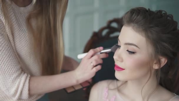 Στυλίστας κάνει μακιγιάζ του μοντέλου. το κορίτσι σε ένα φόρεμα κοκτέιλ ετοιμάζεται για τον εορτασμό — Αρχείο Βίντεο
