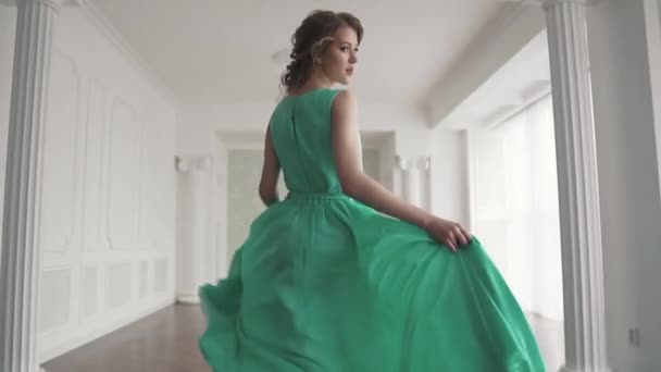 Uma menina na moda em um vestido fluttering foge da câmera e olha ao redor. o tecido flutters lindamente. câmara lenta — Vídeo de Stock