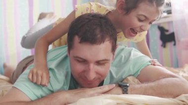 mutlu küçük kızı babalar sırtında tırmanıyor ve onu öper. Genç baba küçük kızı ile eğleniyor