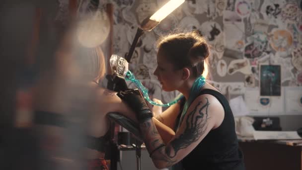 Een tatoeage puttend uit de schouder close-up. Master tattoo maakt een rotary tattoo machine gun — Stockvideo