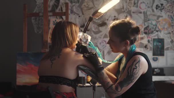 Rita en tatuering på axeln på nära håll. Master tatuering gör en roterande tatuering kulspruta — Stockvideo