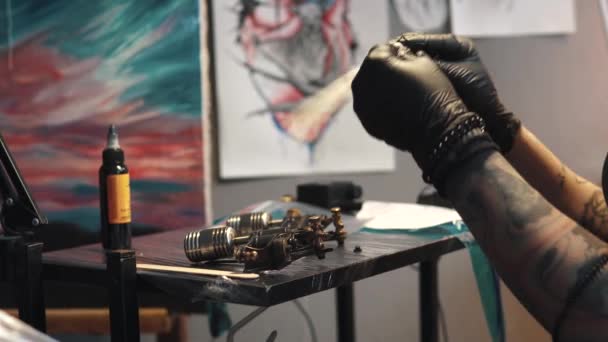 Καλλιτέχνης τατουάζ συλλέγει το μηχάνημα τατουάζ. κορίτσι τατουάζ πλοίαρχος ετοιμάζει ένα πολυβόλο περιστροφική τατουάζ για την κατάρτιση ενός σχεδίου πάνω στο δέρμα — Αρχείο Βίντεο
