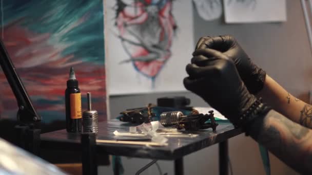 Artista de tatuagem coleta a máquina de tatuagem. Mestre de tatuagem menina prepara uma metralhadora de tatuagem rotativa para desenhar um desenho na pele — Vídeo de Stock