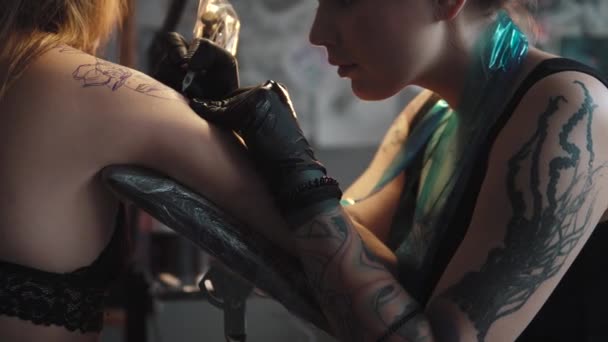 Een tatoeage puttend uit de schouder close-up. Master tattoo maakt een rotary tattoo machine gun — Stockvideo