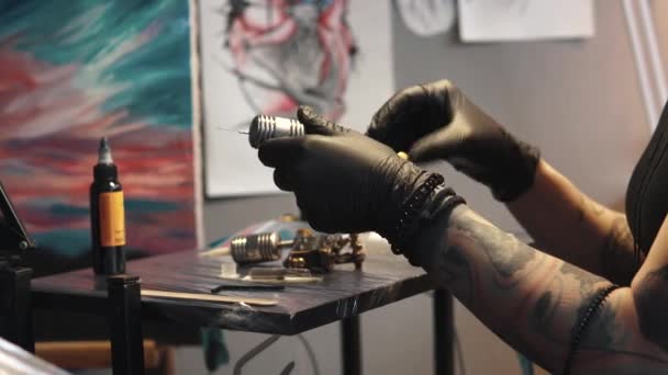 tetováló művész gyűjti a tetoválás gép. lány tetoválás mester készül egy rotációs tetoválás géppuska rajz rajz a bőrön