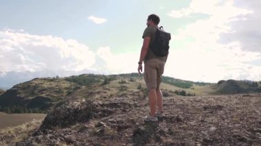 bir adam bir sırt çantası turist ile dağların görünümünü hayran. dağlarda genç yolcusu