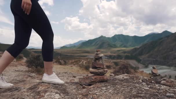 Жінка-туристка робить піраміду з каменів. мандрівник у горах — стокове відео