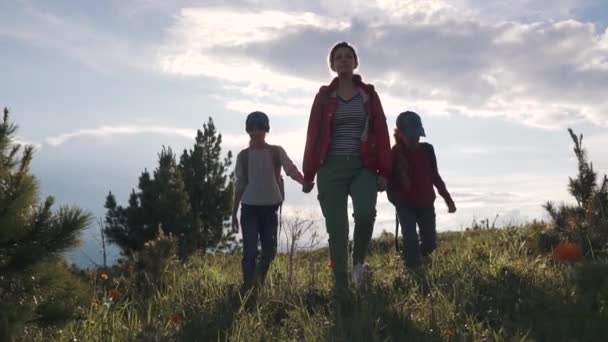 Familia de turistas en un viaje. madre con dos hijas en la campaña. niños con mochilas admiran la vista de las montañas. joven mujer va con niños en las montañas . — Vídeos de Stock