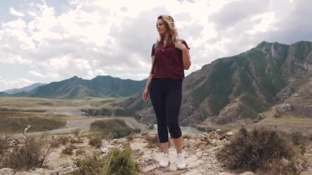 Retrato de una turista femenina en el fondo de las montañas. viajero con una mochila — Vídeos de Stock