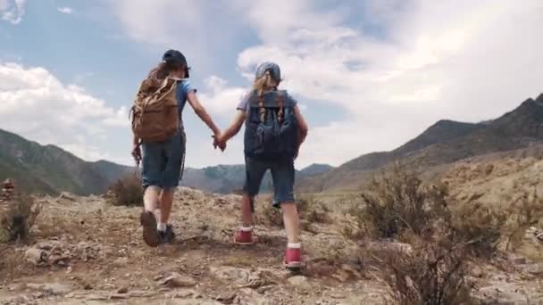 带背包的儿童旅行者。冒险和新发现的概念。两个小女孩走在山的背景下 — 图库视频影像