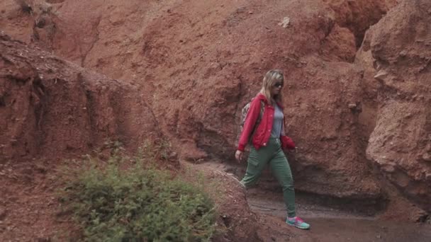 Flicka färdas längs en ovanlig terräng. röd jord och berg, som på Mars — Stockvideo