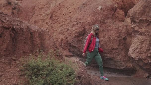 Ragazza viaggia lungo un terreno insolito. terra rossa e montagne, come su Marte — Video Stock