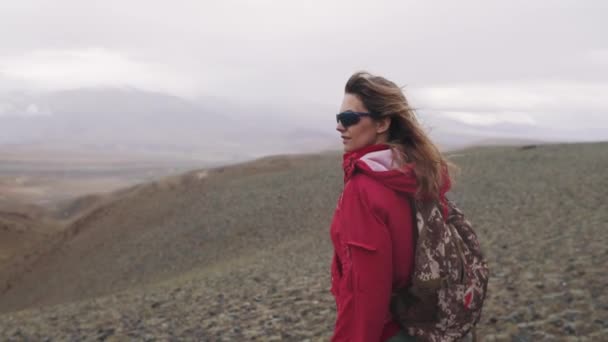 Ritratto di un viaggiatore in montagna sotto la pioggia battente. una ragazza turistica sola con uno zaino negli altopiani. turismo estremo — Video Stock