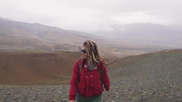 Viaggiatore in condizioni estreme. la ragazza è un turista che cammina lungo il terreno montuoso sotto la pioggia . — Video Stock