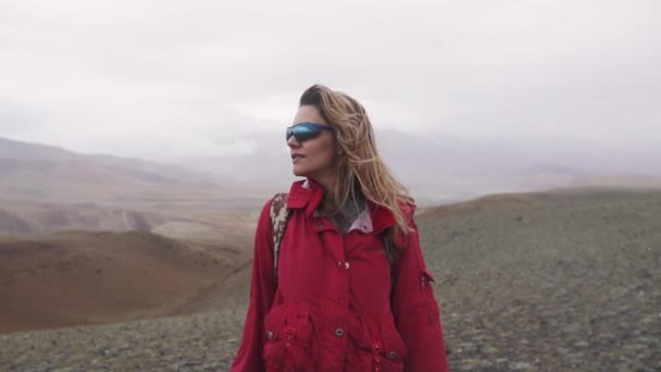 Портрет странницы под дождем в горах. молодая девушка туристка на вершине горы — стоковое видео