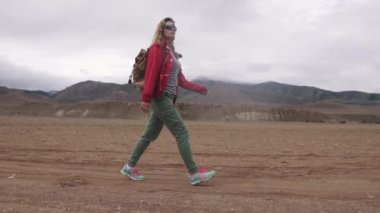 dağlarda bir sırt çantası ile bir turist portresi. kız gezgin sert hava dağlık arazide yürür