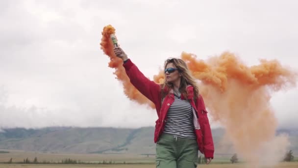 Podróżny daje znak i przyciąga uwagę kolorowe dymu. turystyczna dziewczynka gospodarstwa bomba dymu. zwolnionym tempie — Wideo stockowe