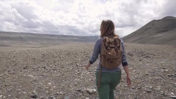 Turista menina vai em um terreno montanhoso. retrato do viajante. mulher caminhante com mochila, montanhas no fundo . — Vídeo de Stock