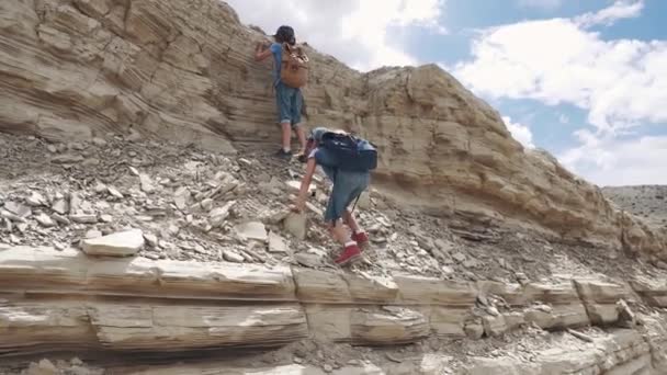 As crianças escalam a rocha. pequenos viajantes com mochilas. duas meninas em uma caminhada nas montanhas — Vídeo de Stock