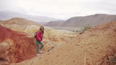 Gezgin dik bir yokuş yükselir. bir turist kız bir sırt çantası ve dağlık arazi yürüyüş giyen güneş gözlüğü.