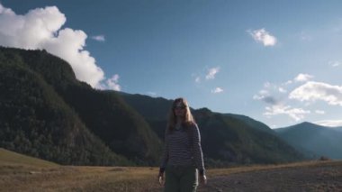 bir turist kız yakın çekim portresi. Bir gezgin bir sırt çantası ve dağlık arazi giyen güneş gözlüğü yürür.
