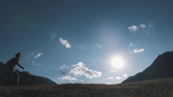 Silhouet van een reiziger in de achtergrond van bergen en de lucht. het toeristische meisje loopt langs de bovenkant van de heuvel — Stockvideo