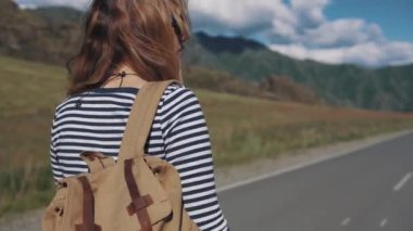 Gezgin kadın yakın çekim portresi. Kız Turizm karayolu boyunca gidiş bir sırt çantası ile. Arkadan görünüm