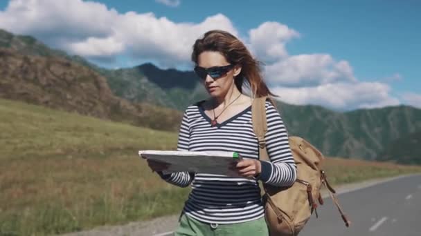 Porträt einer reisenden Frau aus nächster Nähe. das Touristenmädchen mit einer Papierkarte in der Hand läuft die Autobahn entlang — Stockvideo